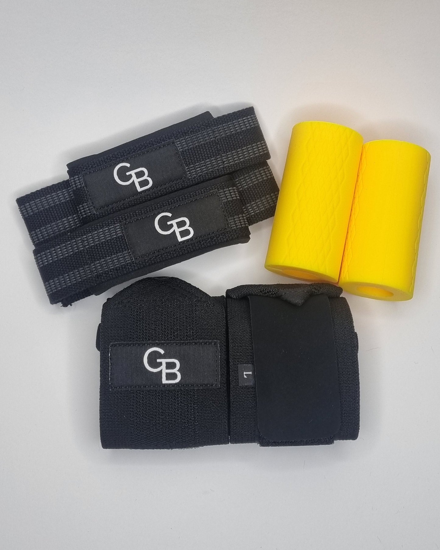 Black wrist wraps with yellow foam roller on a white surface